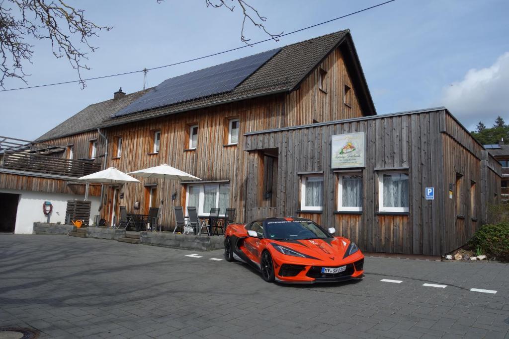 een oranje auto geparkeerd voor een houten gebouw bij Speedys Gästehaus in Baar