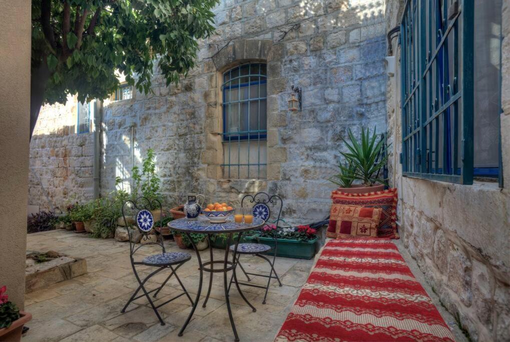 een patio met een tafel en stoelen op een tapijt bij Courtyard Suite, Artists' Quarter, Tzfat in Safed