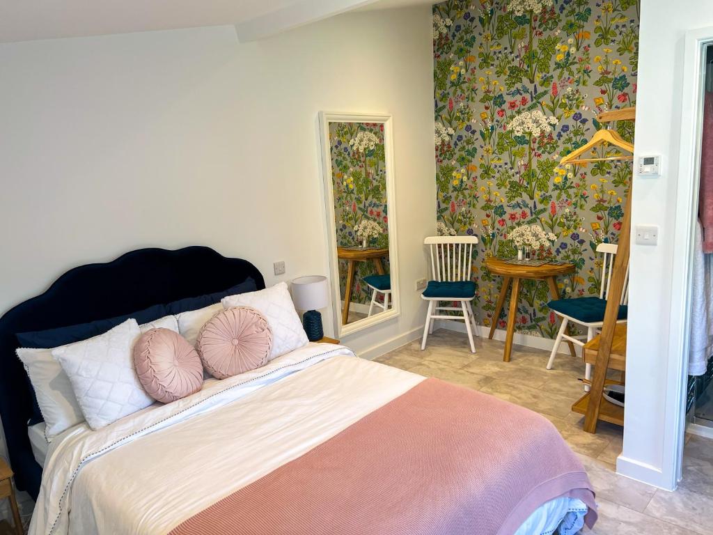 1 dormitorio con 1 cama grande con almohadas rosas en The Annexe, en Bruton