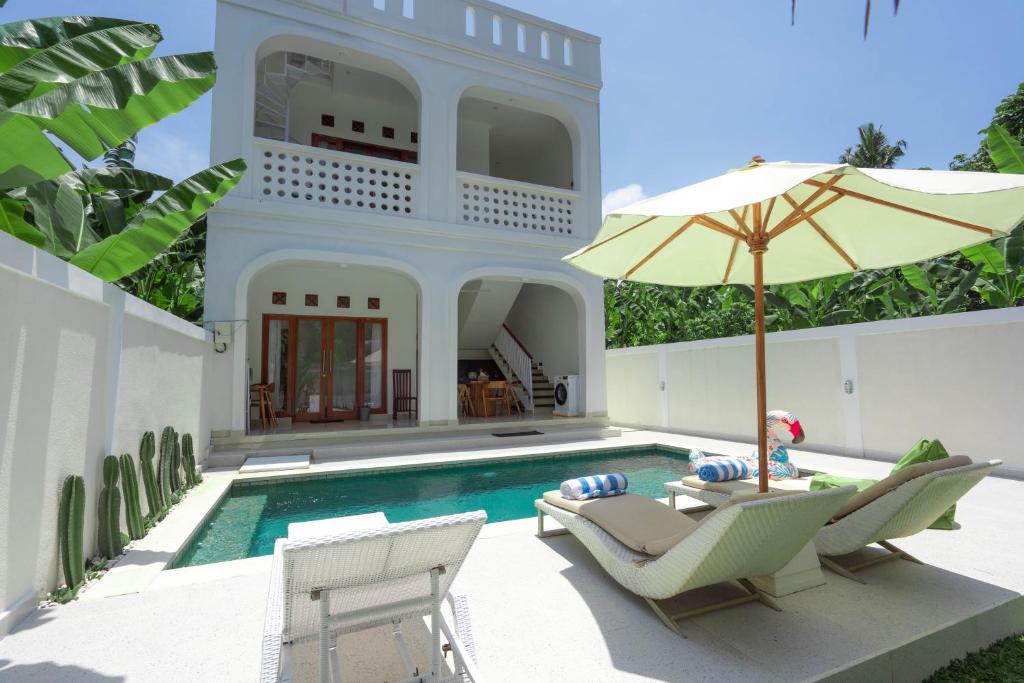 une maison dotée d'une piscine avec des chaises et un parasol dans l'établissement The Lavana La Bliss Villa North, à Munggu