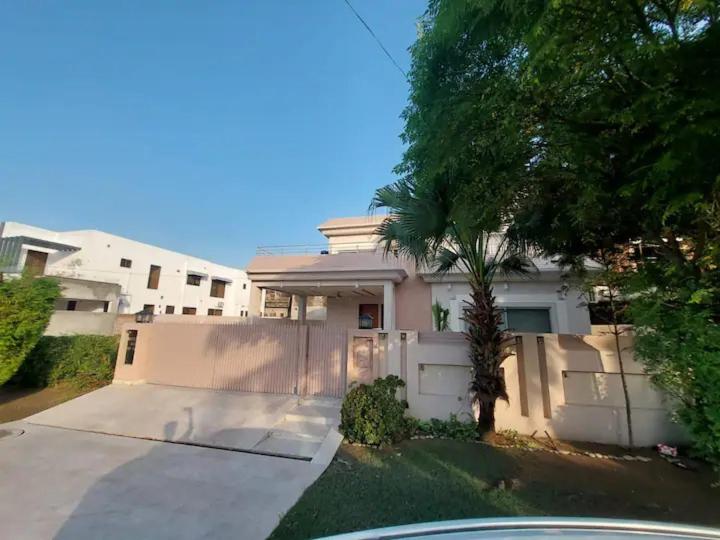 ein weißes Haus mit einem Zaun und einem Baum in der Unterkunft 5 Bedrooms furnished separate upper portion house in DHA Phase 4, Lahore in Lahore