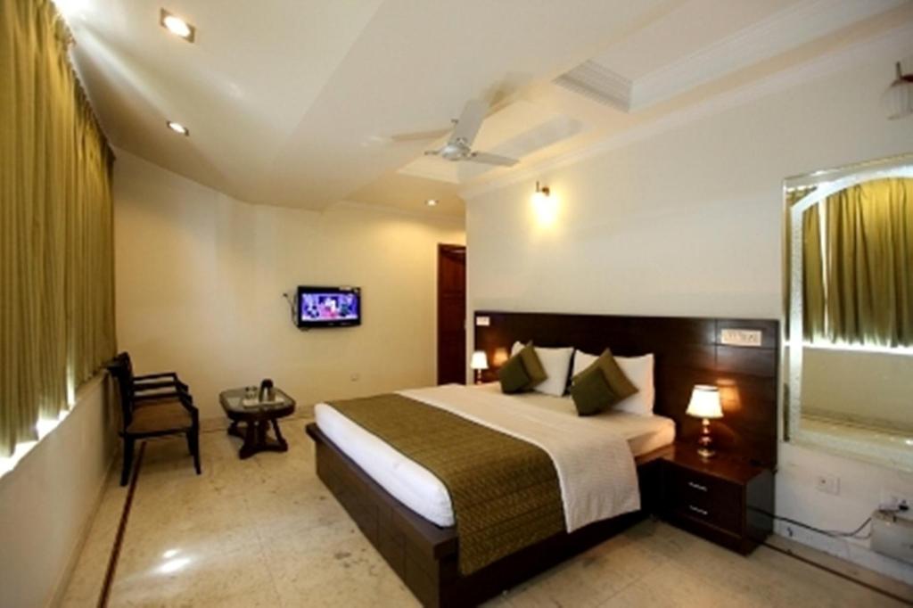 um quarto de hotel com uma cama e uma televisão em Hotel Krone A Family Hotel Near IGI Airport em Nova Deli