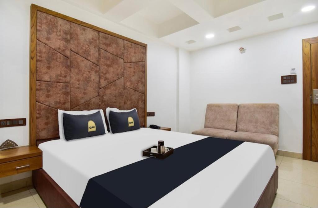 a bedroom with a large white bed and a chair at Hotel Palace in Chandrapur