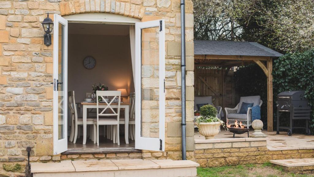 an open door to a patio with a table and chairs at Wild Pear Cottage in Wolford
