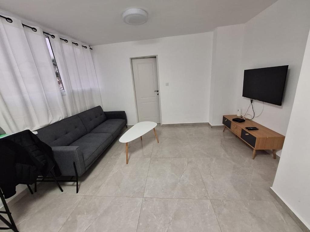een woonkamer met een bank en een tv bij המקום של אתי ולילך 2 in Eilat