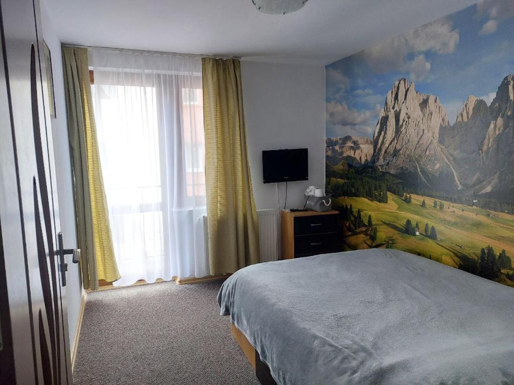 een slaapkamer met een bed en een schilderij aan de muur bij Vila Foc Alb Apartamente-Busteni in Buşteni
