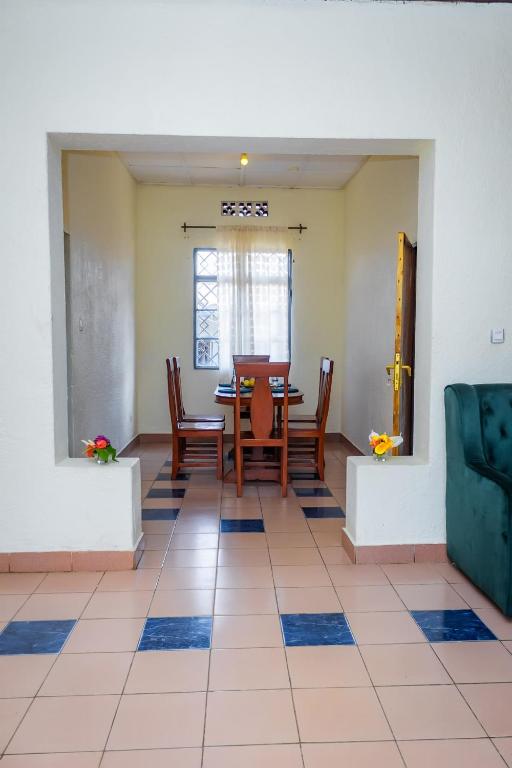 a dining room with a table and chairs on a tiled floor at Rhoja homes in Ruhengeri