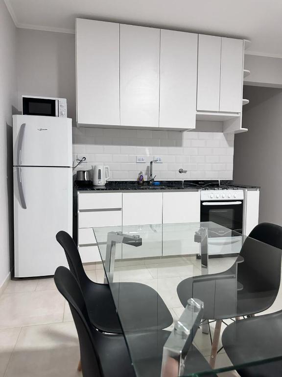 uma cozinha com armários brancos, uma mesa de vidro e cadeiras em RIFFEL 2 em Aldea Camarero