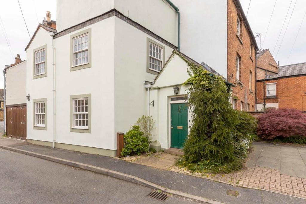 a white house with a green door on a street at Independence House in Oakham