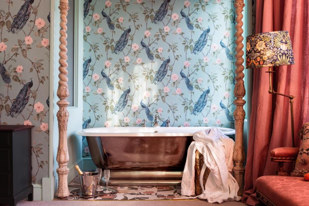 uma banheira num quarto com papel de parede floral em The Portobello Hotel em Londres