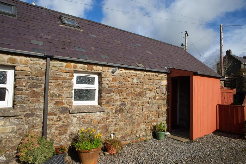 an old stone house with a red door and windows at Bay Cottage Little Haven in Little Haven