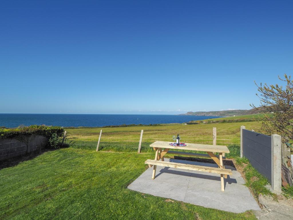 a picnic table in the grass with a view of the ocean at Hiraul Aberporth in Aberporth