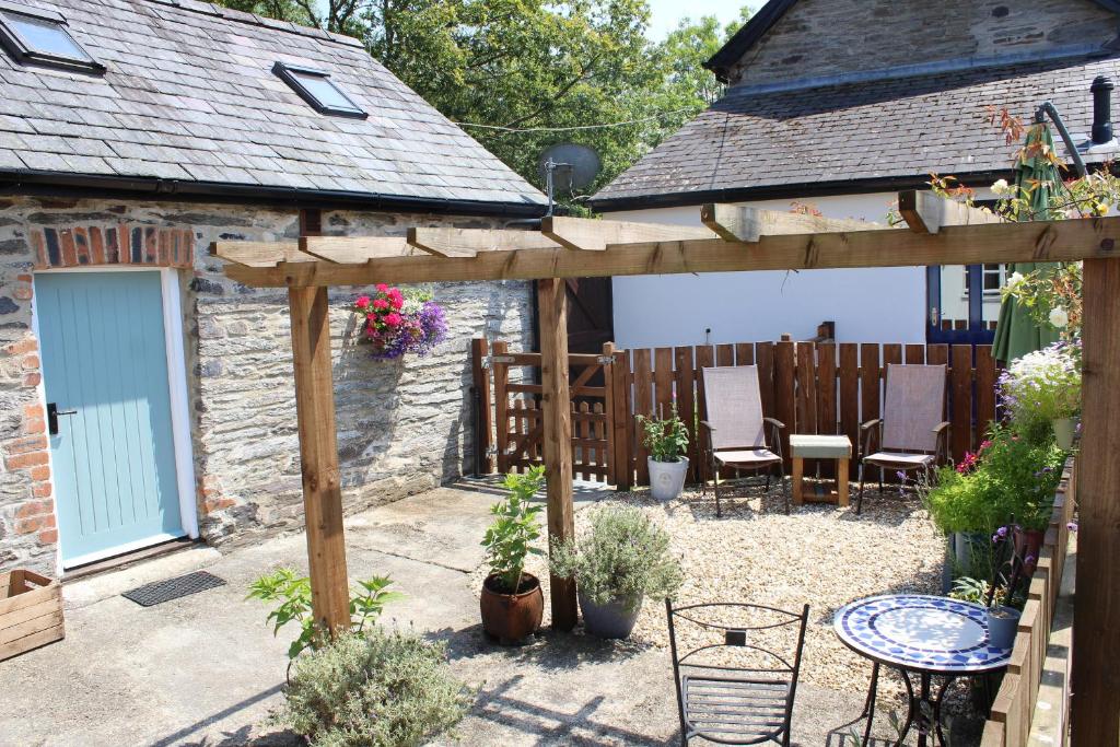 un jardín con pérgola de madera, mesa y sillas en The Old Stables Brongest en Troedyraur