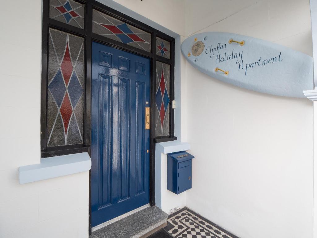 a blue door on a white wall with stained glass windows at Clydfan Apartment Aberporth in Aberporth
