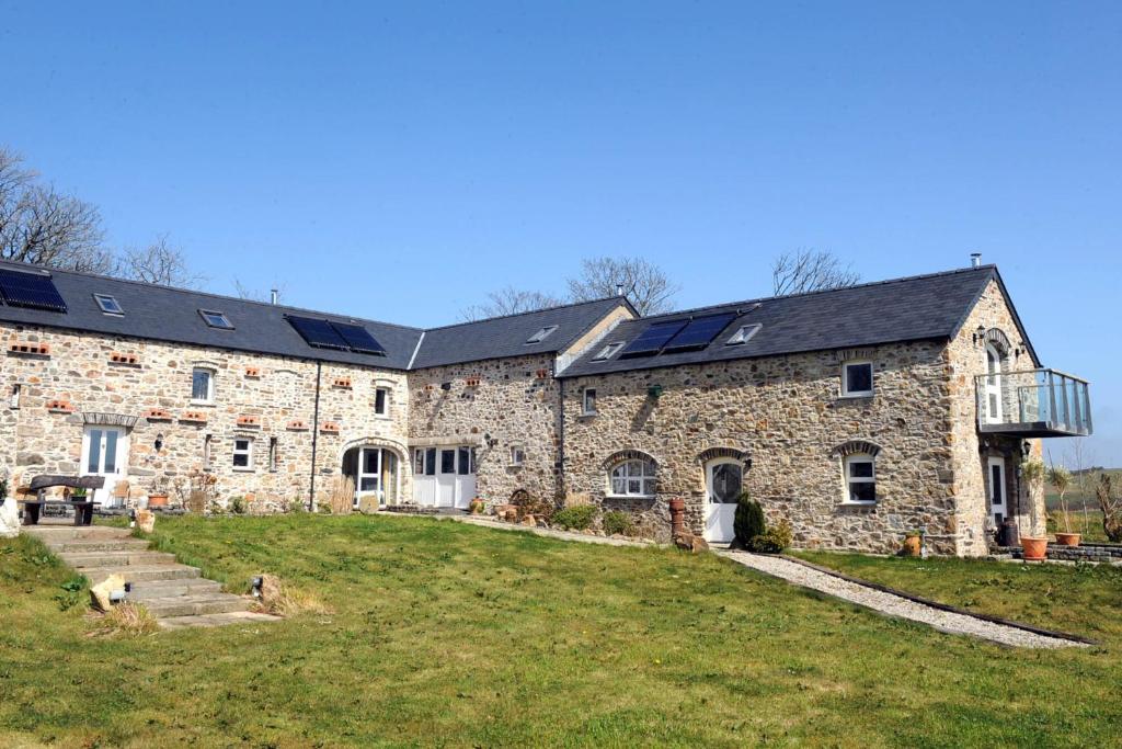 a large stone building with solar panels on it at The Grain Store Newgale in Llandeloy