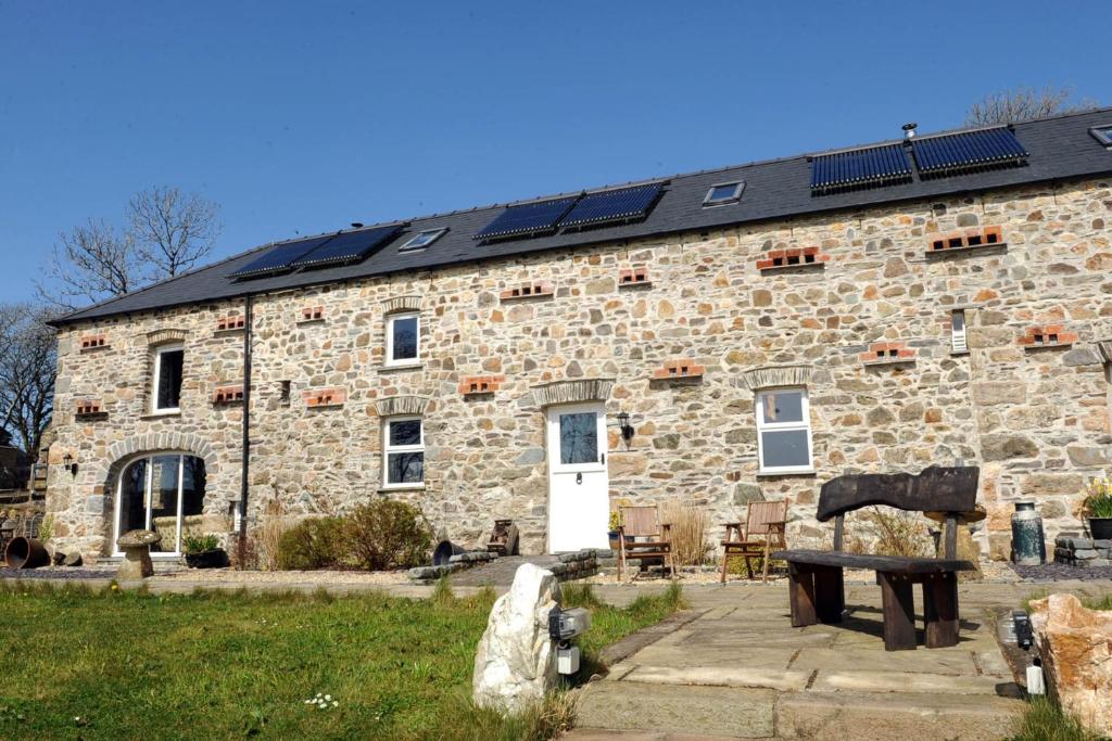 a stone building with solar panels on the roof at The Stables Newgale in Llandeloy