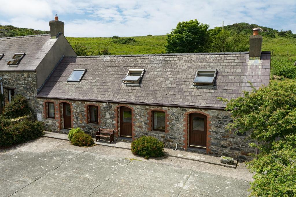 an old stone house with windows and a roof at Cnwc Y Bran St Nicholas in Saint Nicholas