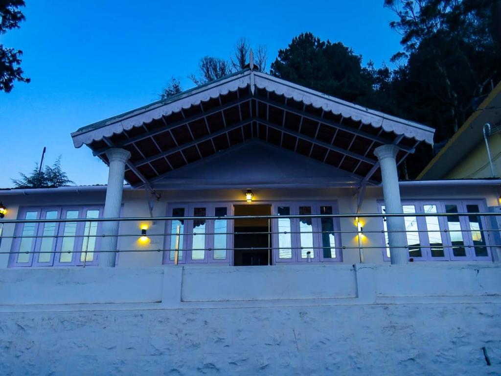 a large white house with a porch at night at BOB's Haven Bungalow in Ooty