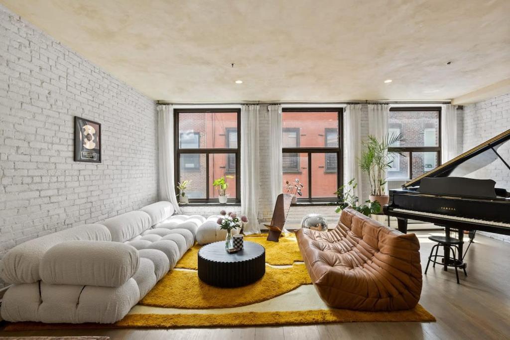 Tribeca Loft Vanderbilt by RoveTravel في نيويورك: غرفة معيشة مع أريكة وبيانو