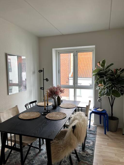 a dining room table with a white dog sitting around it at Moderne lejlighed i hjertet af Odense C in Odense