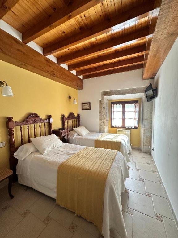 two beds in a room with wooden ceilings at Casa Rural El Torrejon in Arenas de Cabrales