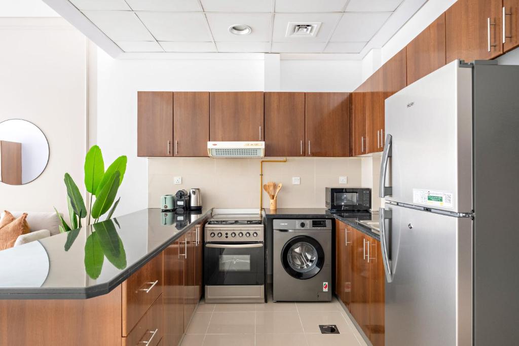 a kitchen with wooden cabinets and a washer and dryer at Silkhaus Modern Studio Near Silicon Central Mall in Dubai