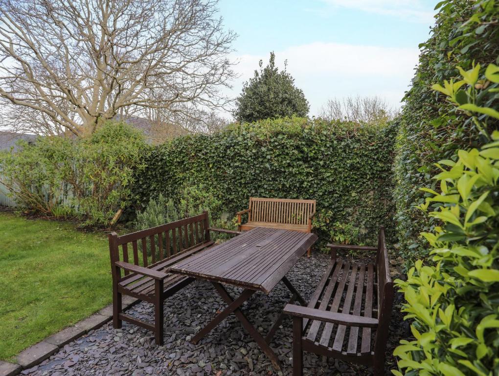 a wooden picnic table and two benches in a garden at Amelie Cottage in Beaumaris