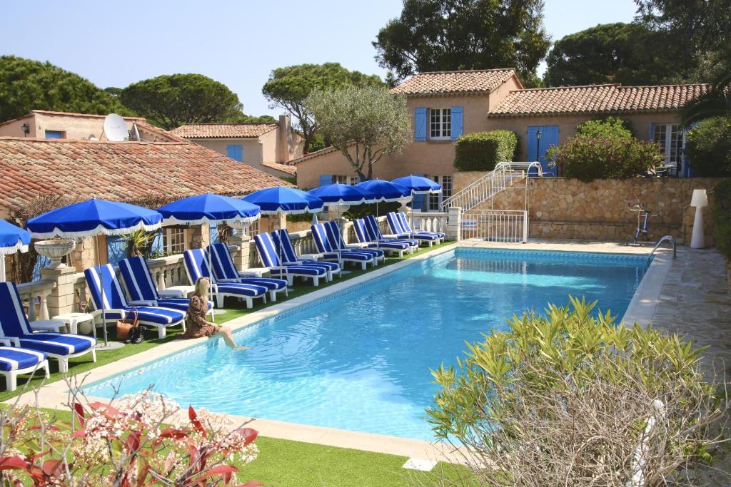 una piscina con sedie blu e ombrelloni di Hôtel Jas Neuf a Sainte-Maxime