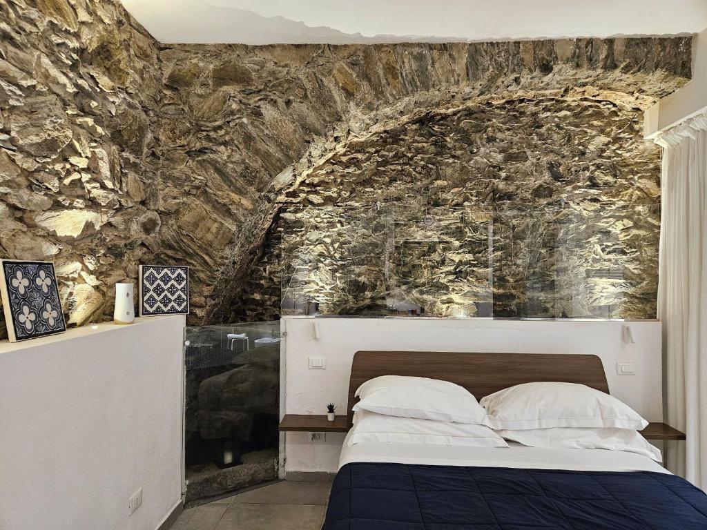 1 dormitorio con 1 cama y pared de piedra en ca' di sotto, en Riomaggiore