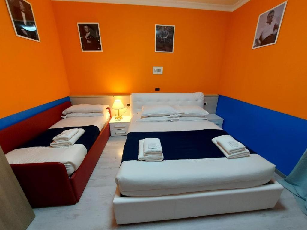 two beds in a room with an orange wall at Hotel Positano Suite in Rome