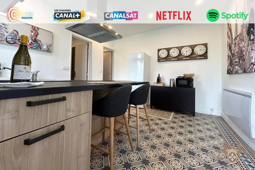 a kitchen with a bar with two stools at Le Traveller - COSY FLAT Senlis in Senlis