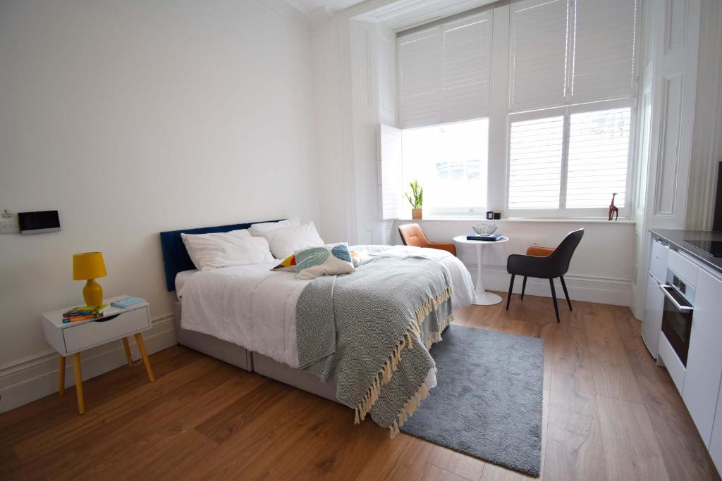 a white bedroom with a bed and a window at Kensington Studios in London