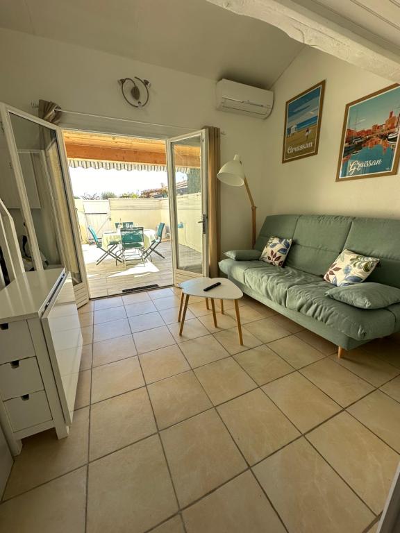 een woonkamer met een bank en een tafel bij La Discrète toute équipée avec piscine in Gruissan