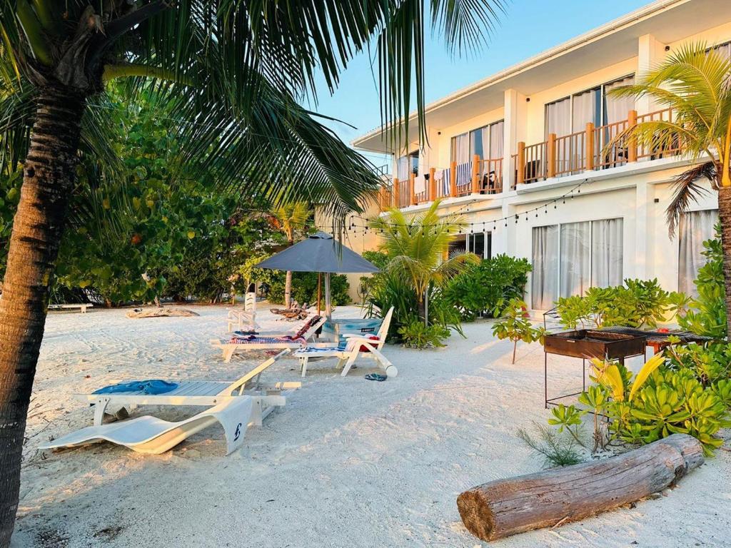 a beach with chairs and an umbrella and a hotel at The Sunset Villa in Dhiffushi