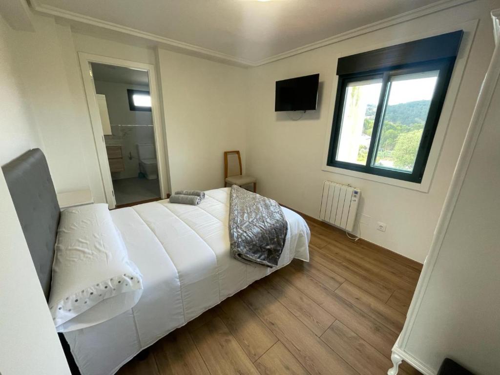 Un dormitorio con una gran cama blanca y una ventana. en Posada Celtia, en Vigo