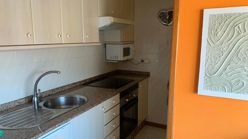 a small kitchen with a sink and a microwave at Precioso ático en Playa América a 200 metros de la playa in Nigrán