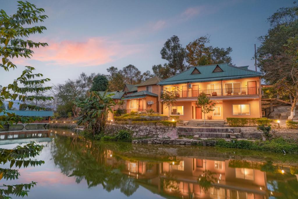 a house with a river in front of it at Summit Green Lake Tea Resort & Spa in Kāziranga