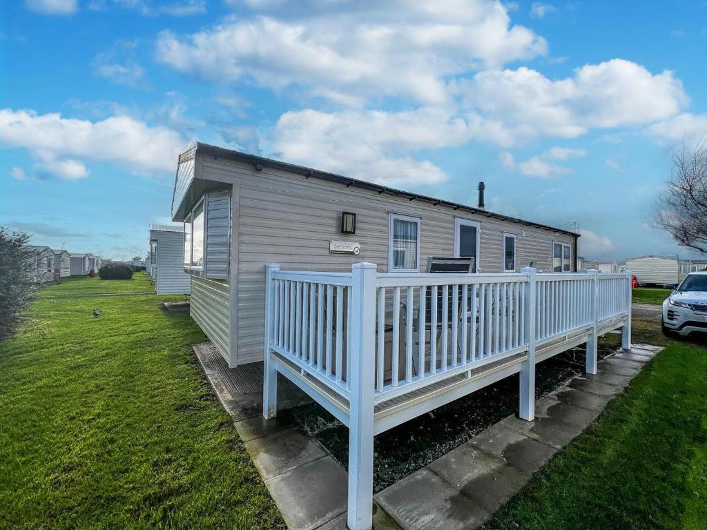 a white house with a porch and a fence at Luxury Caravan With Decking And Wifi At Haven Golden Sands Ref 63069rc in Mablethorpe