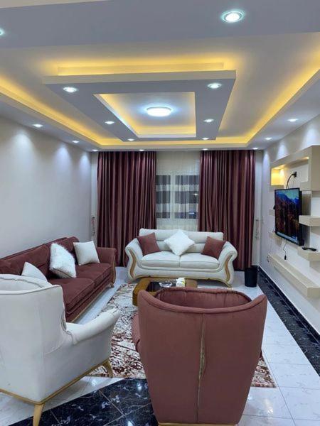 un soggiorno con divani e TV a schermo piatto di شقة فندقية للايجار a Il Cairo