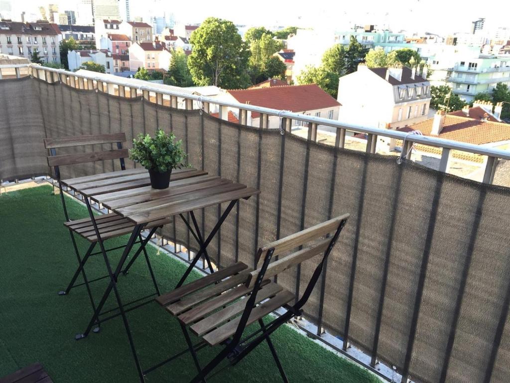 une table en bois et deux chaises sur un balcon dans l'établissement Les Maisons Acajou - Ivry-sur-Seine, à Ivry-sur-Seine