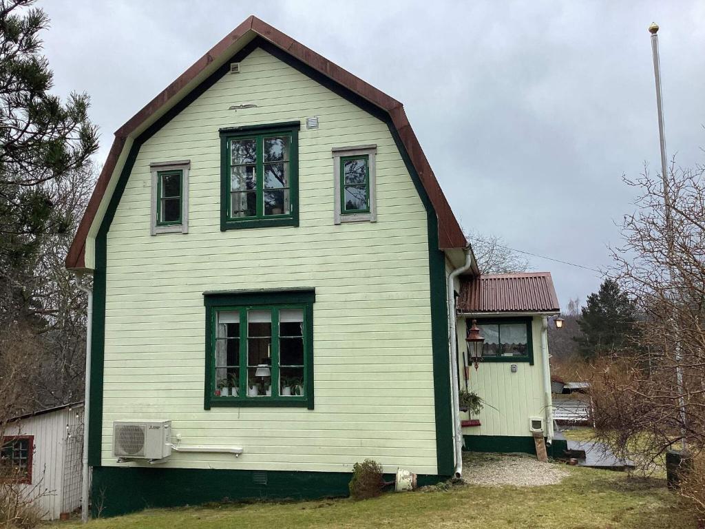 ein grünes und weißes Haus mit zwei Fenstern in der Unterkunft Holiday home HÅVERUD in Håverud