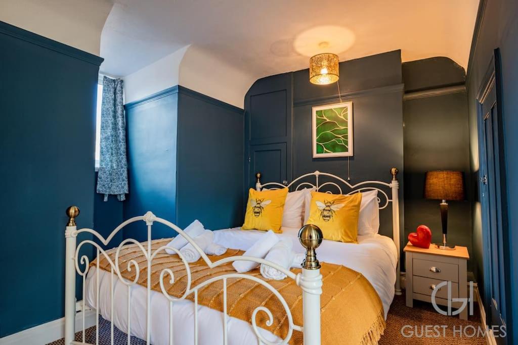 1 dormitorio con 1 cama con paredes azules y almohadas amarillas en Guest Homes - Station Approach en Purley