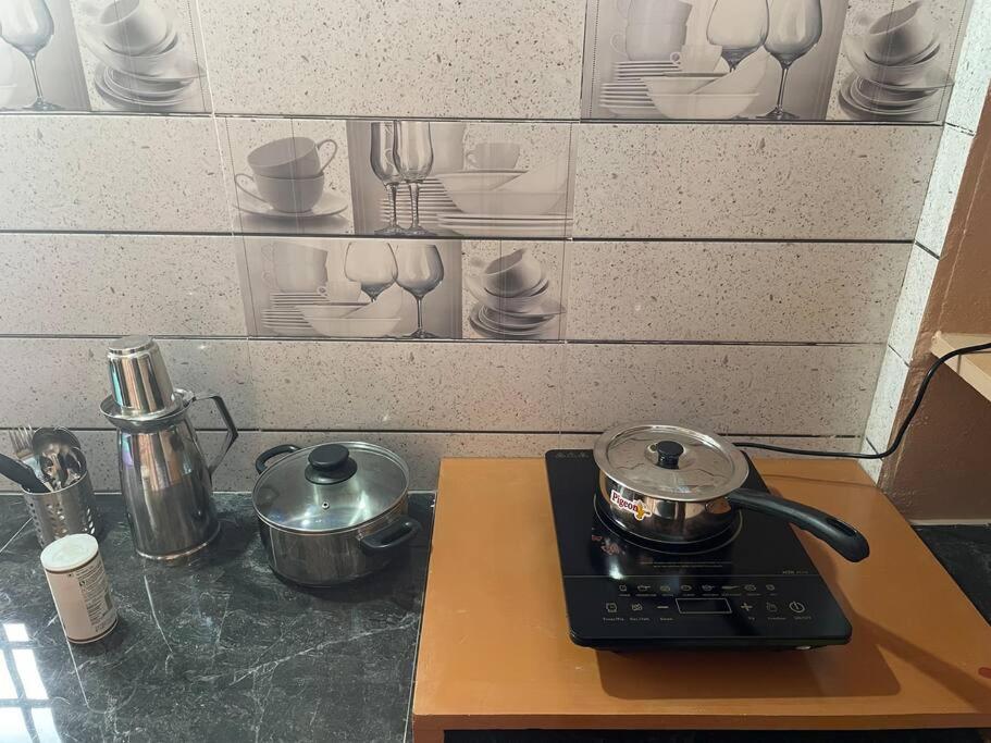 a kitchen counter with pots and pans on a stove at Om Sai Nilayam Guest house in Tirupati