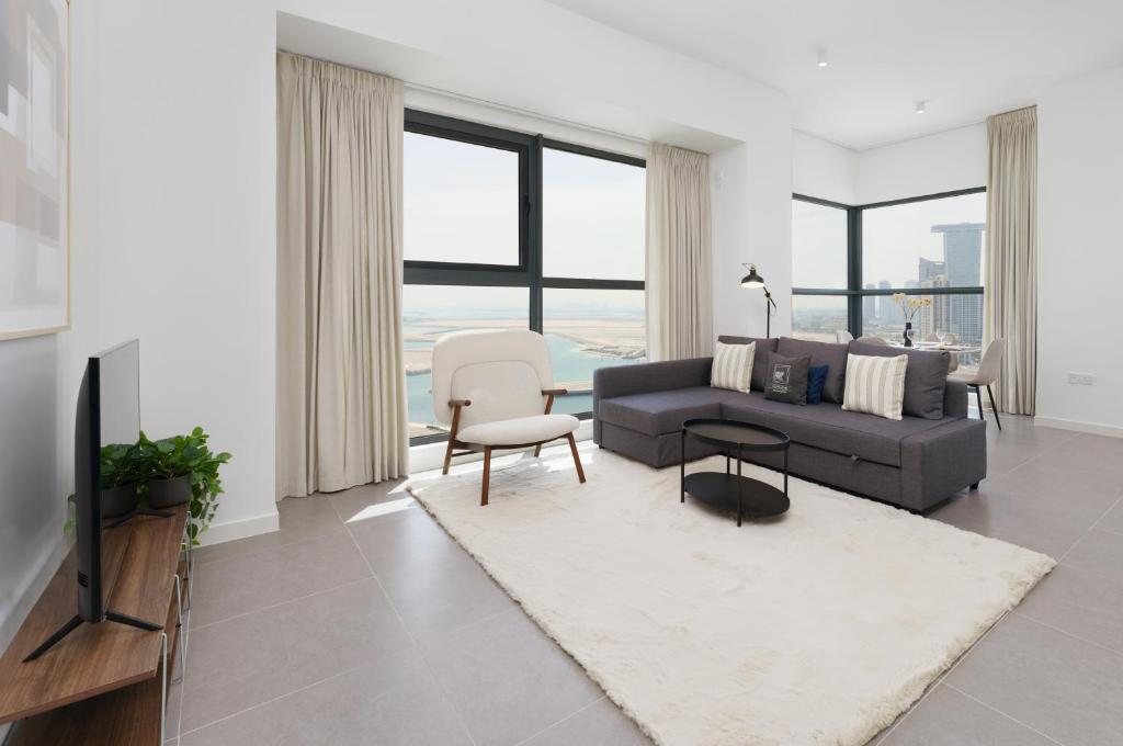 a living room with a couch and a table at Maison Privee - Modern & Panoramic Sea View Apt on Al Reem Island in Abu Dhabi