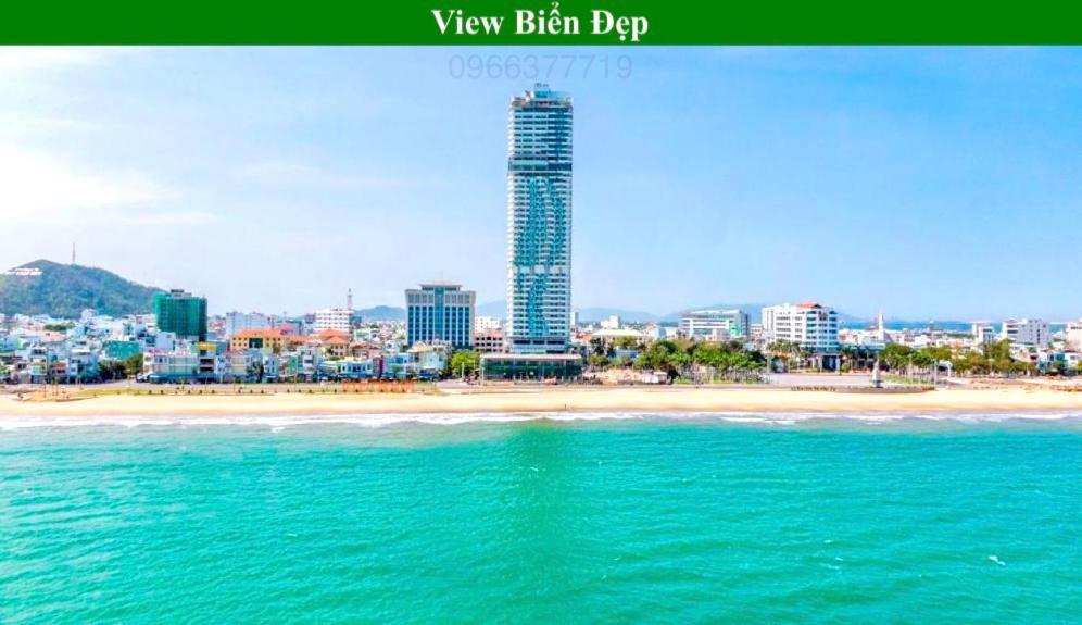 een uitzicht op een strand met een hoog gebouw bij TMS Quy Nhơn View Biển in Quy Nhon