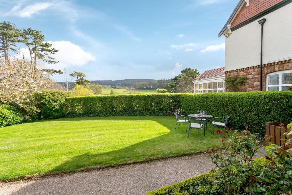 a garden with a table and chairs and a hedge at April Cottage in Minehead