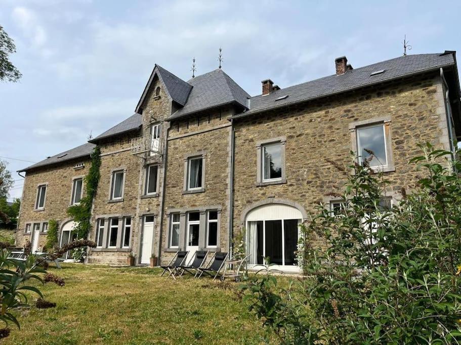 un vieux bâtiment en briques avec des chaises dans une cour dans l'établissement Charmante Gentilhommière, à Daverdisse