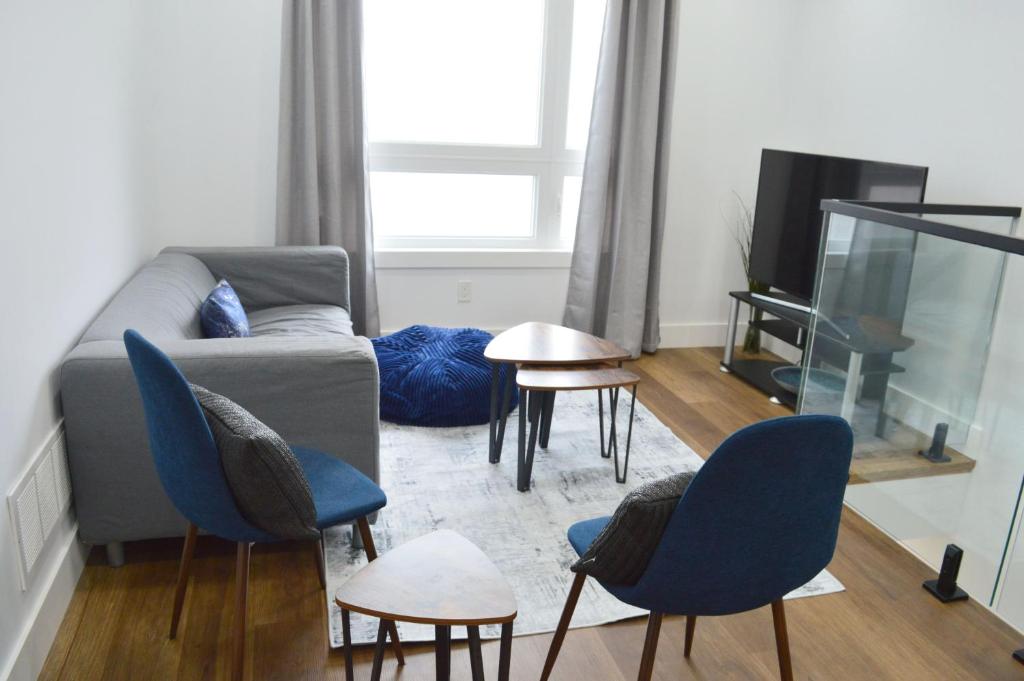 ein Wohnzimmer mit einem Sofa, Stühlen und einem TV in der Unterkunft Modern East York Retreat 20 mins to DT Toronto in Toronto