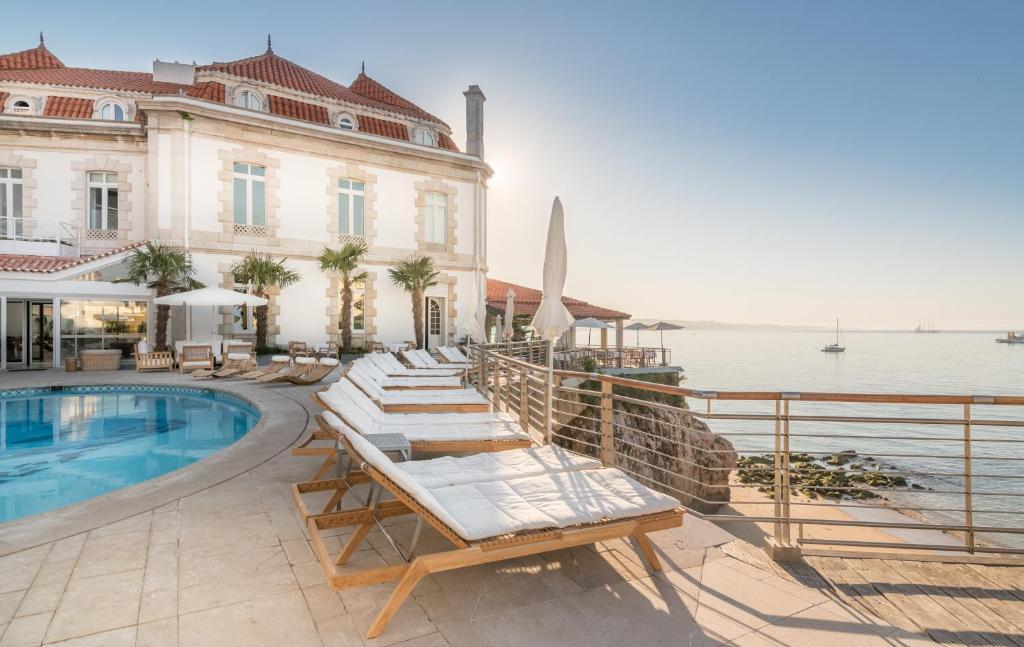 a pool with lounge chairs next to a building at The Albatroz Hotel in Cascais