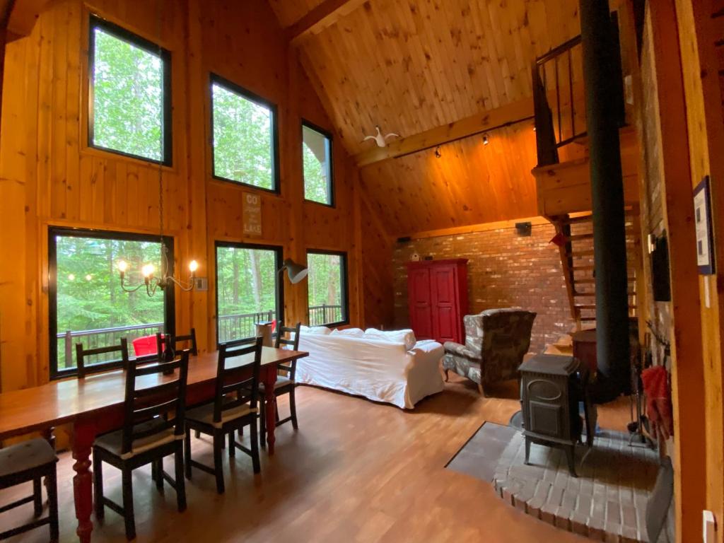 a living room with a table and chairs and a fireplace at Waterfront Chalet Serendipity Hideaway - Cachette Sérendipité - Swim SUPs BBQ Relax w Wifi in Chertsey